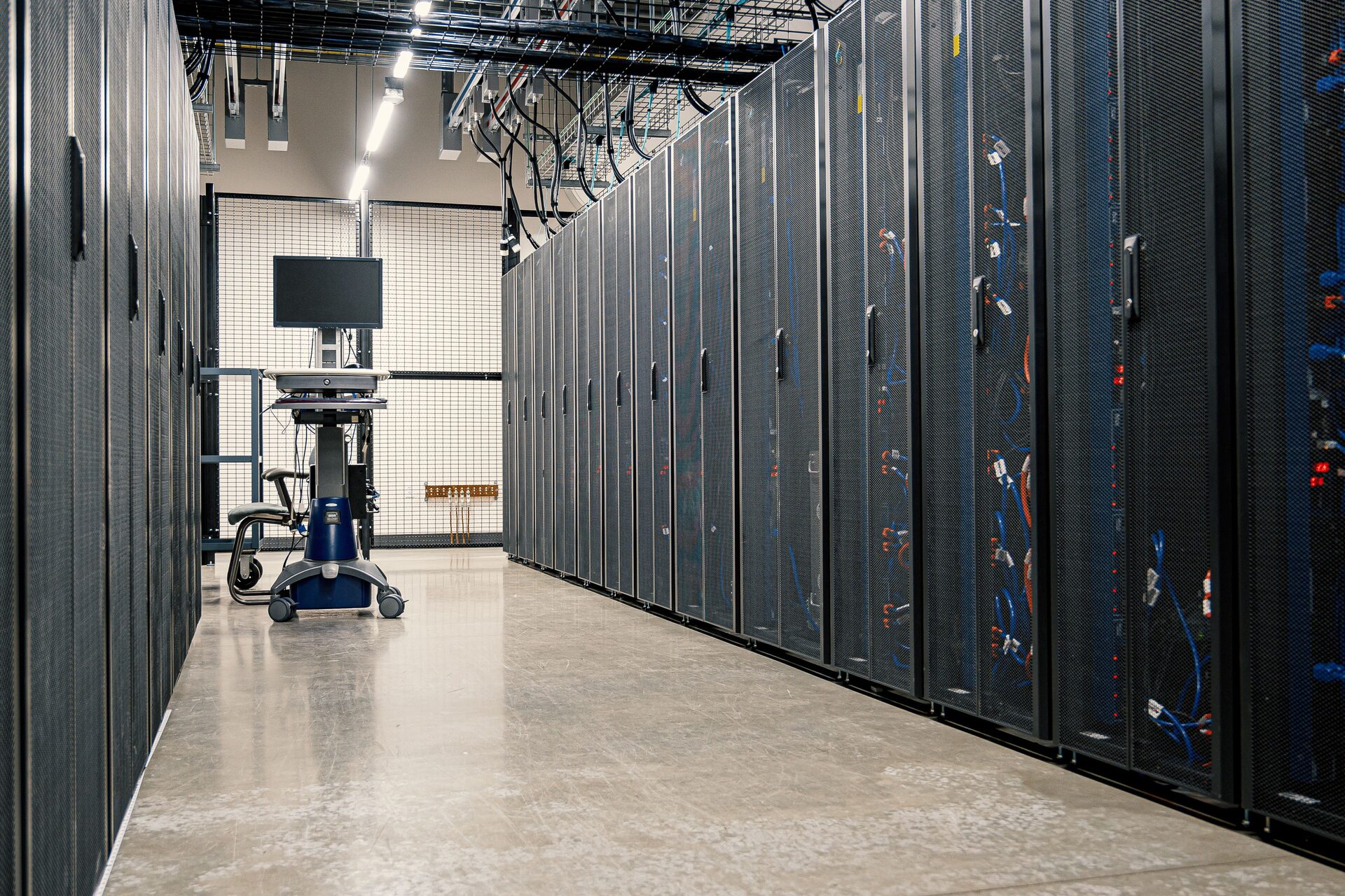 Interior of a carrier-neutral data centre hall showing rows of caged server racks with structured overhead cabling
