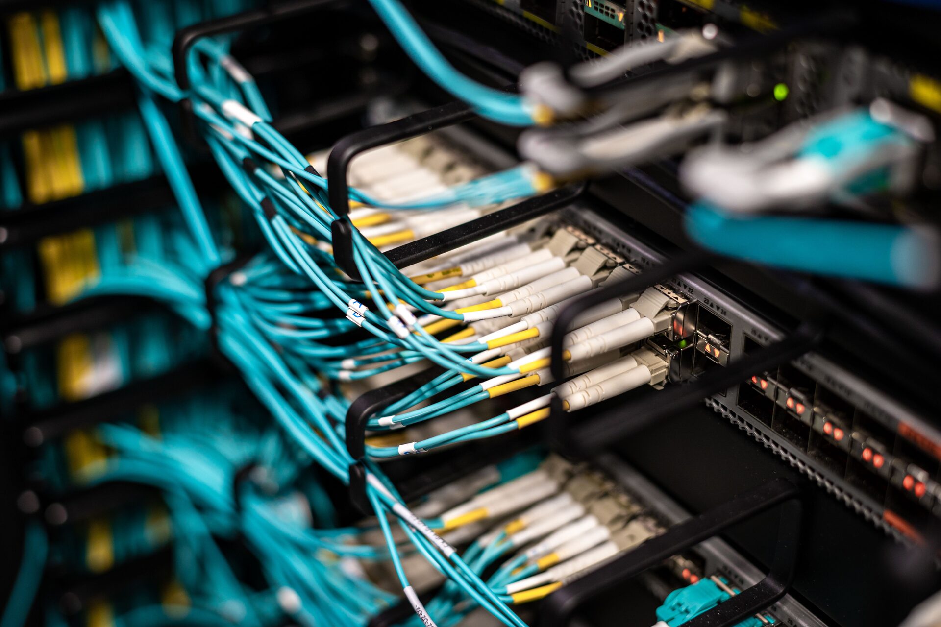 Close-up of SFP transceivers and cyan fibre patch cables connected into a rack-mount switch